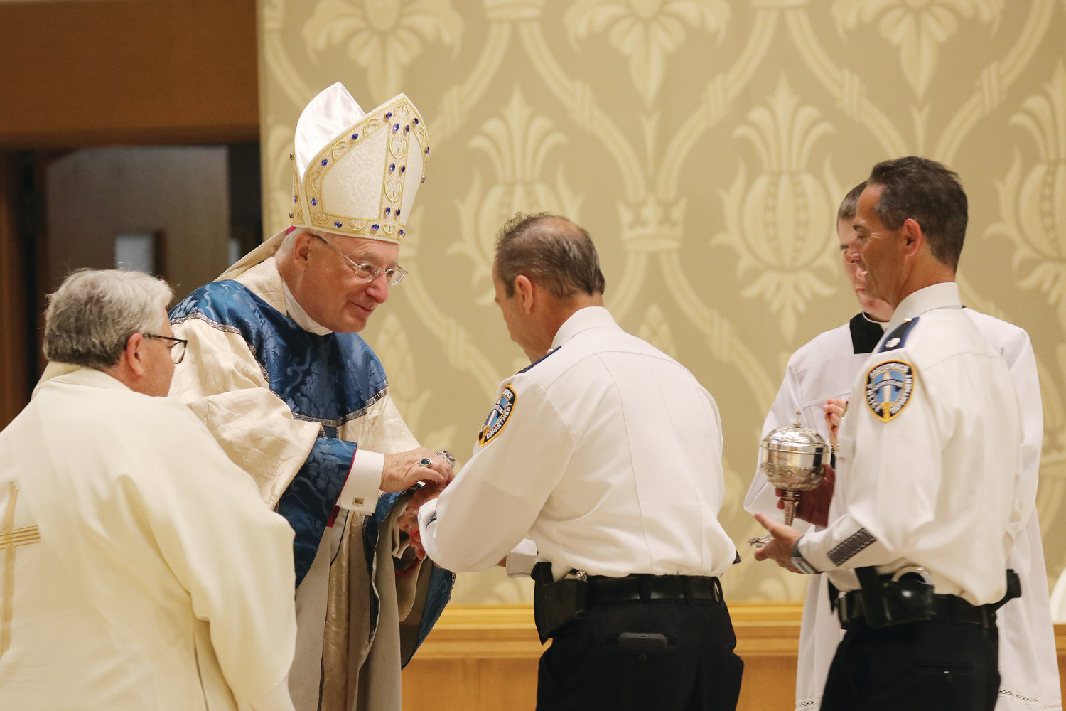 Chief Hugh Clements Jr., left, and Deputy Chief Thomas Verdi present the gifts to Bishop Robert C. Evans during the annual Mass for Public Safety.